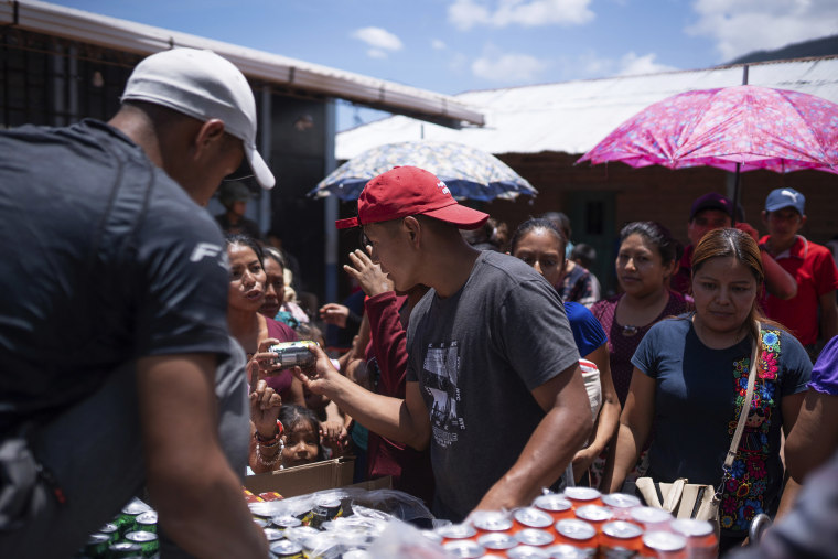 Locals in Guatemala offer sodas to Mexicans who fled their town of Amatenango, Mexico to escape cartel violence in Mexico, Thursday, July 25, 2024. Some refugees are staying at the school and others at locals' homes. 