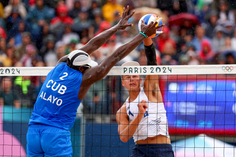 Miles Partain, from the United States team, attacks the net against Jorge Luis Alayo Moliner, from the Cuba team.