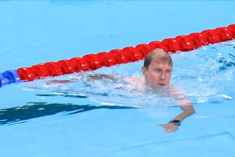 A man swims under a lane marker in a swimming pool