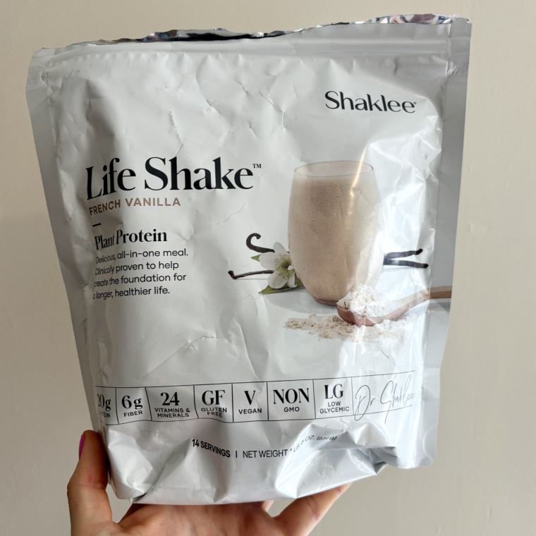 Woman holds Shaklee Life Shake French Vanilla Plant Protein in her hand.