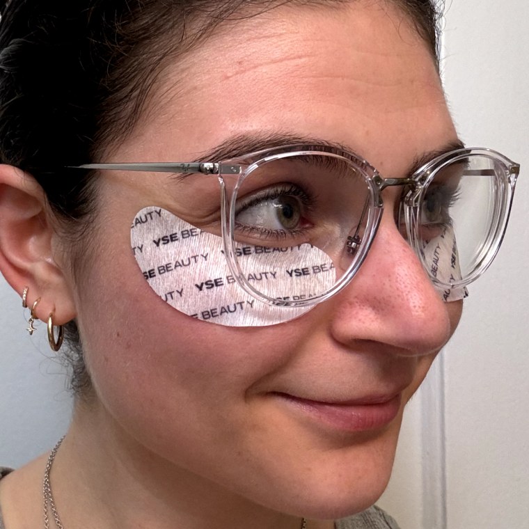 A woman wears Yse masks under her eyes while wearing glasses on top.