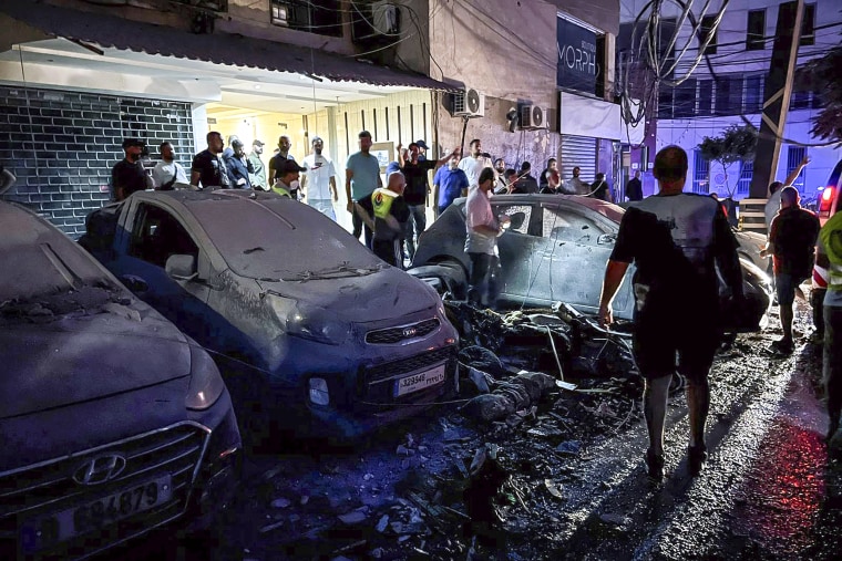 Image: People inspect damaged cars in the southern suburbs of Beirut, Lebanon