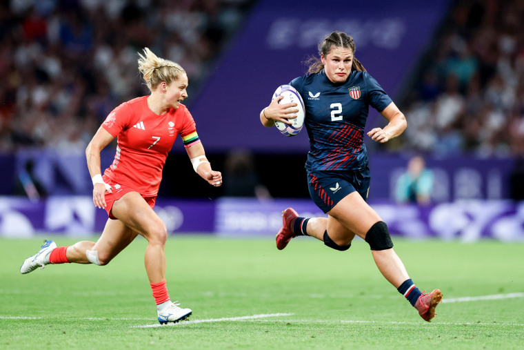 Ilona Maher runs with the ball away from Emma Uren beside her