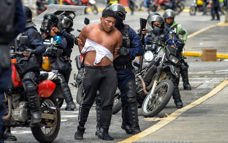 Members of the Bolivarian National police riot squad arrest a protester in Caracas, Venezuela