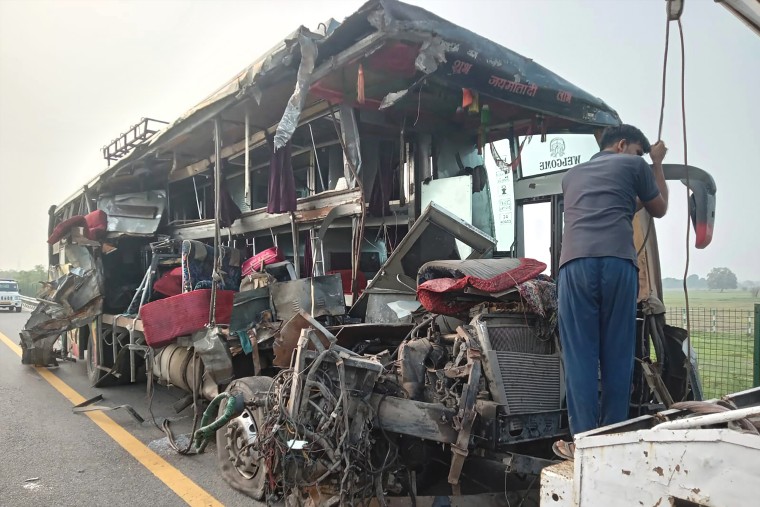 A roadside assistance worker tows away the mangled remains of a double-decker passenger bus that collided with a milk truck, near Unnao, in the northern India state of Uttar Pradesh.
