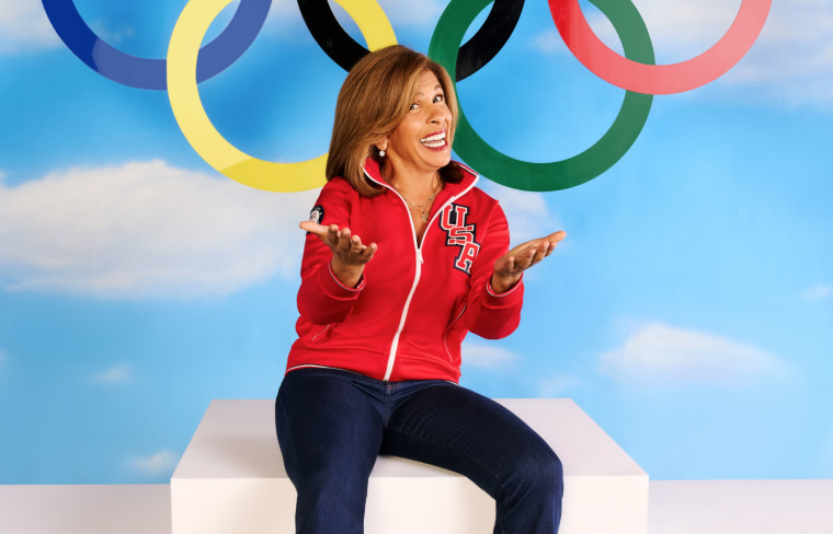 Hoda Kotb poses in front of a blue sky backdrop with Olympic rings