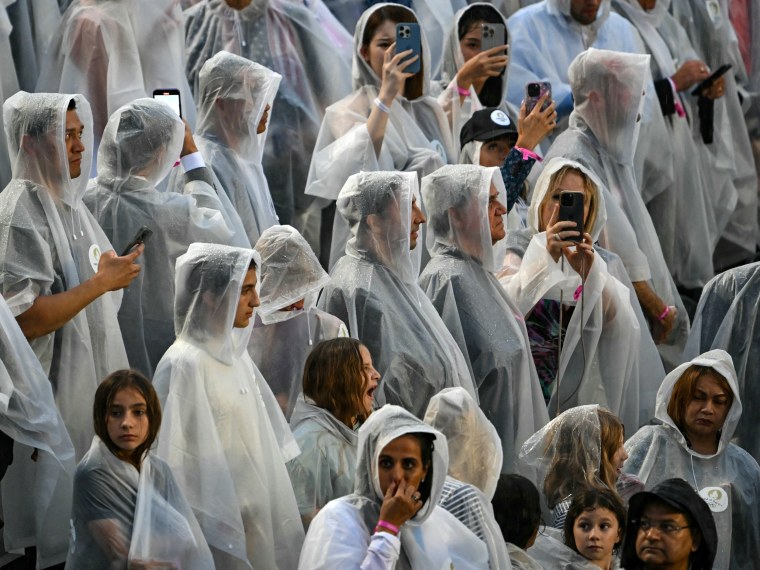 Spectators wear rain covers.