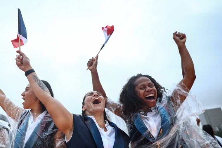 French athlete Yolaine Yengo, right, and fellow athletes from France's delegation react as they sail in a boat along the river Seine. 