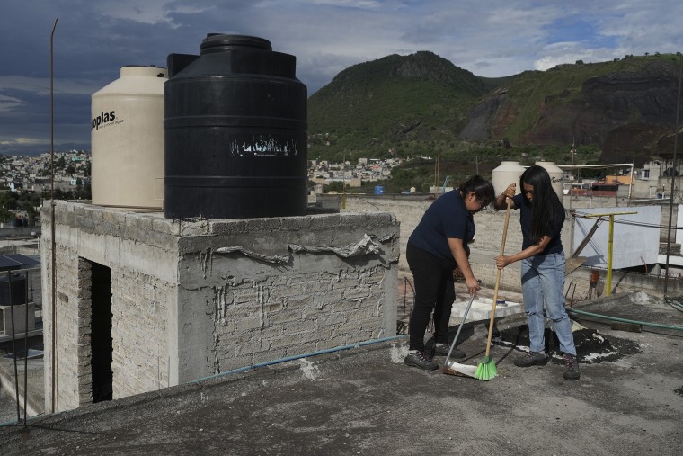 Sonia Estefania Palacios Diaz, left, and Lizbeth E. Pineda Castro, right, clean the roof of a house used to collect rainwater in the Iztapalpa neighborhood in Mexico City on July 21, 2024.