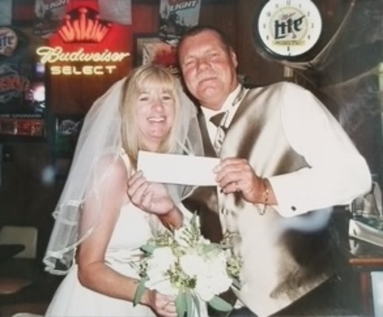 Denise McClure in a bridal gown and Terry McClure in a wedding tuxedo standing in a bar