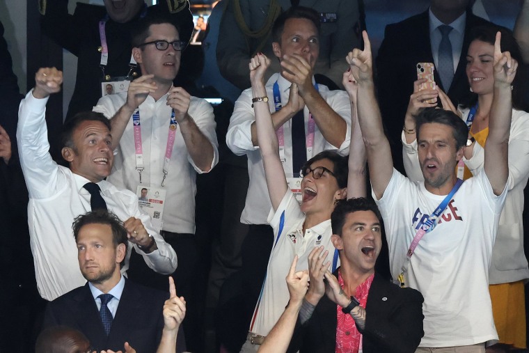 French President Emmanuel Macron celebrates as he attends the evening swimming session, after Leon Marchand 