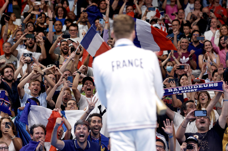 Fans show their support as France's Leon Marchand stands on the podium during the Swimming medal ceremony after the Men's 200m Individual Medley Final on day seven of the Olympic Games Paris 2024 at Paris La Defense Arena on August 02, 2024 in Nanterre, France.