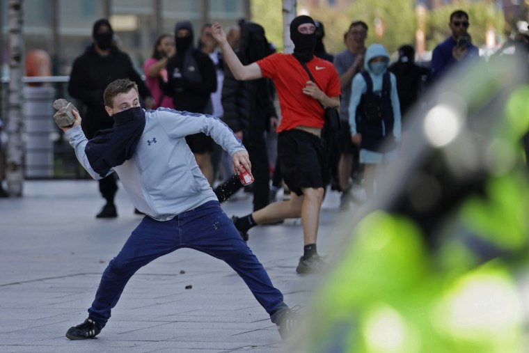 A demonstrator throws a brick during a protest in Liverpool