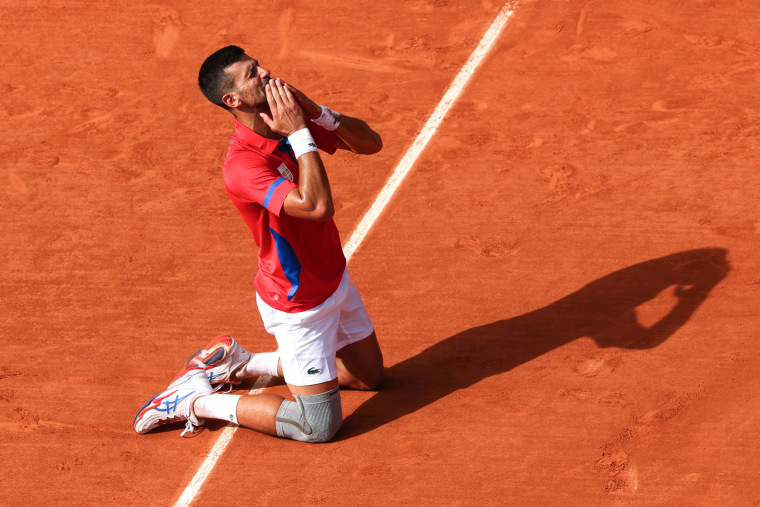 Novak Djokovic kneels down and kisses his hands in celebration