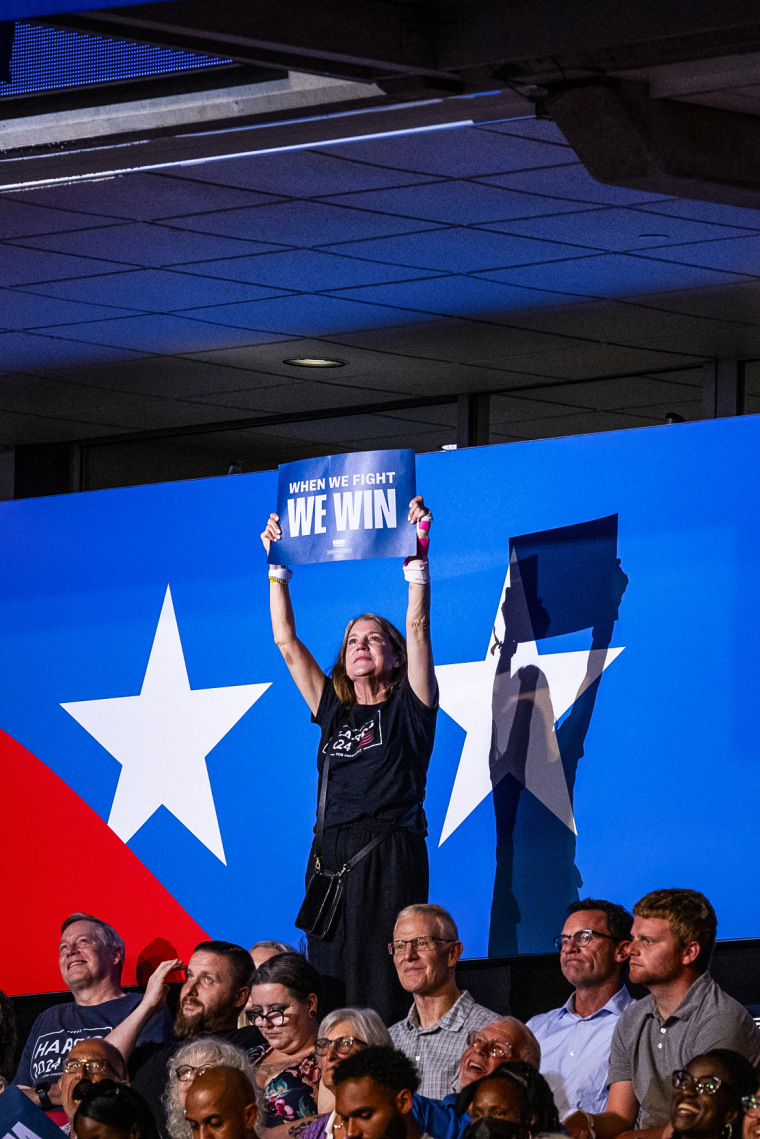 A woman holds a sign with the slogan “When We Fight We Win” during a campaign rally