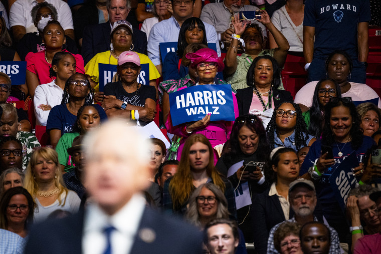 A woman holds a campaign sign as Minnesota Governor Tim Walz speaks to the crowd