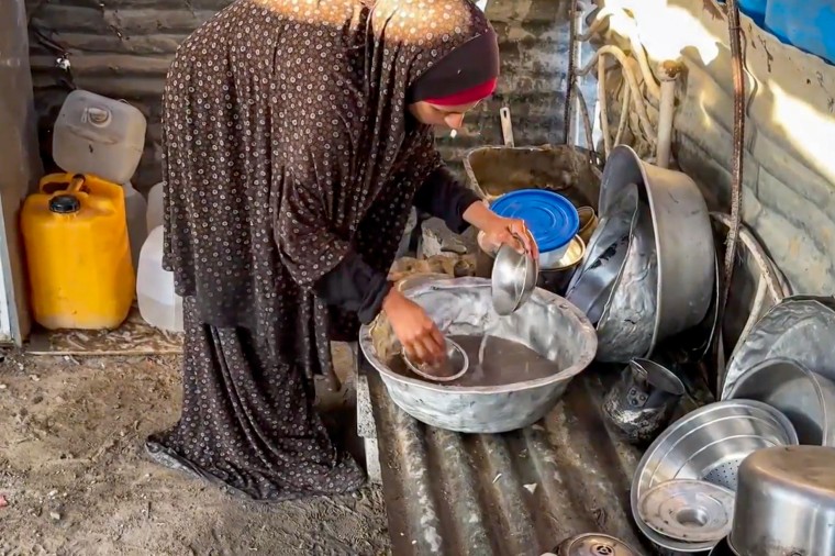 A woman rinses dishes.