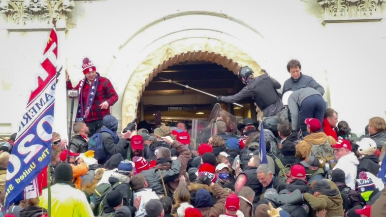 David Dempsey swings a pole near the top of a crowd of Capitol rioters