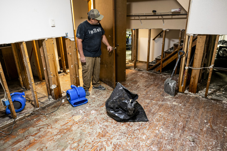 Citizens remove wet drywall and insulation on the ground level of a split-level home.