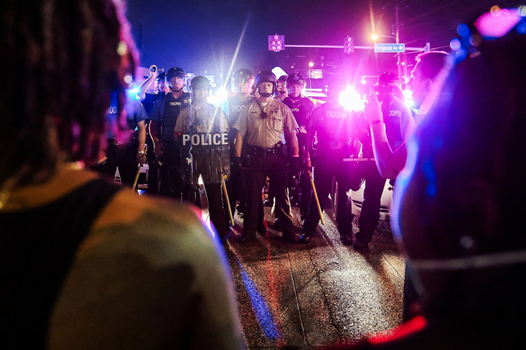 St. Louis County Police and Missouri State Highway Patrol troopers stand guard on the street at night ahead of protestors