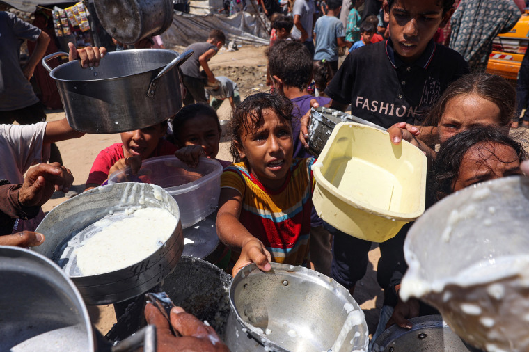 Displaced Palestinian children wait at a food distribution point in Deir el-Balah in the central Gaza Strip on August 8, 2024