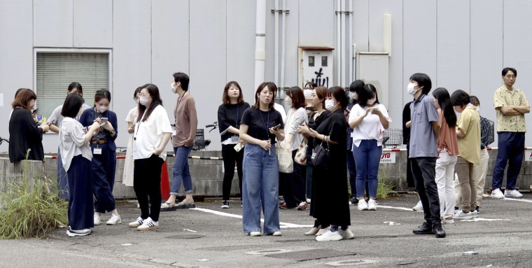 地震以来、建物から出てきた人々が外に立っている