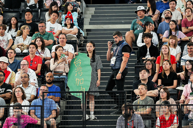 Um membro da segurança pede a um torcedor que segura uma faixa em referência a Taiwan que deixe a arquibancada durante uma partida de badminton.