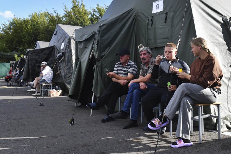 People evacuated from Russia's Kursk region sit next to tents at a temporary residence center on August 12, 2024. 