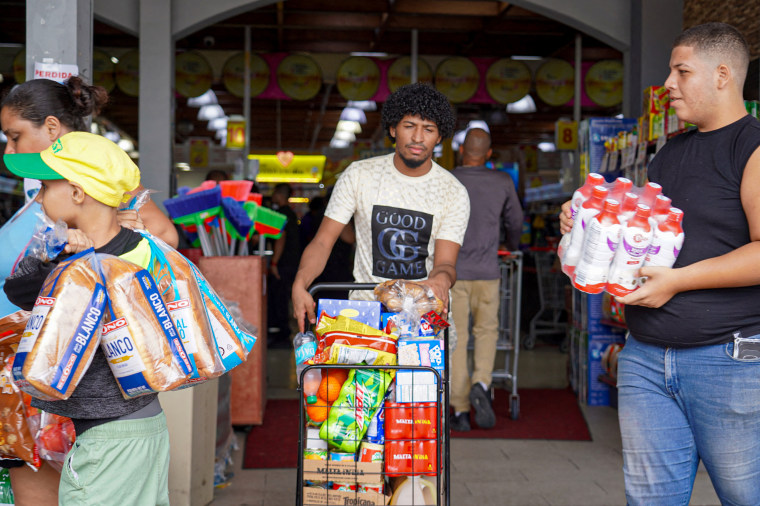 People leaving the supermarket with groceries.