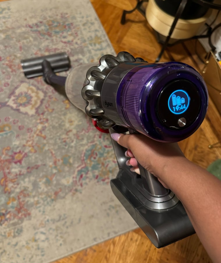 A close up angle of a Dyson vacuum being used on a carpet.