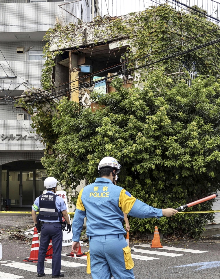 Image: Police stand outside a damaged building following an earthquake in Miyazaki, western Japan