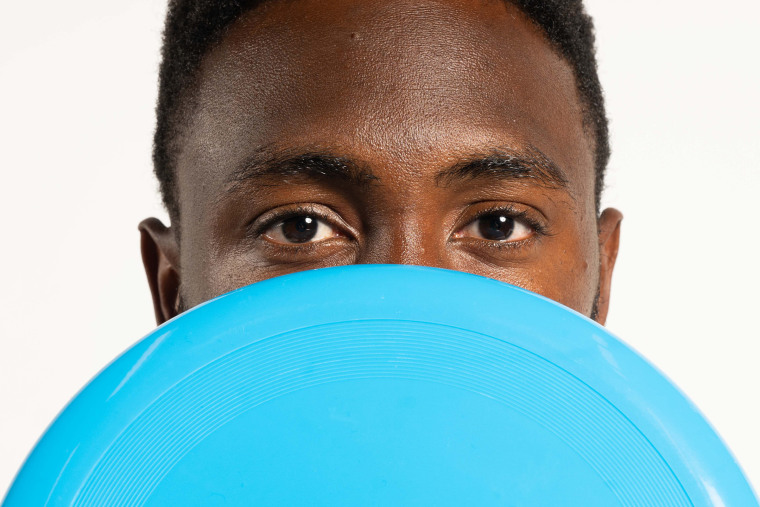 Marques Brownlee holding a blue frisbee in front of his face.