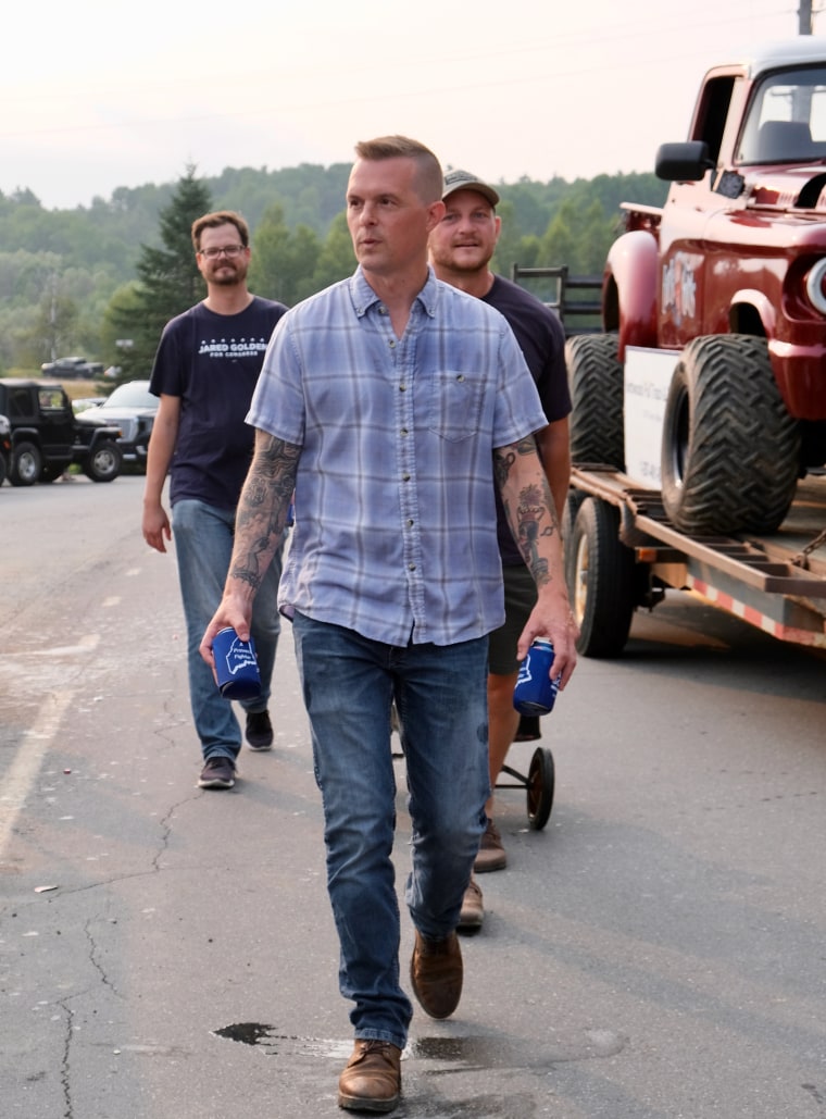 Jared Golden holds beers in both hands while walking on the street outside