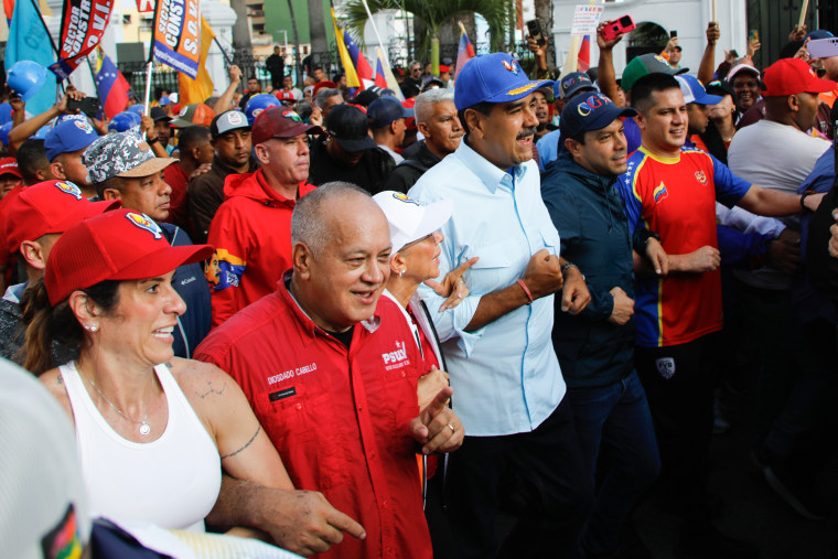 Nicolás Maduro, Cilia Flores e Diosdado Cabello marcham do lado de fora no meio de uma multidão