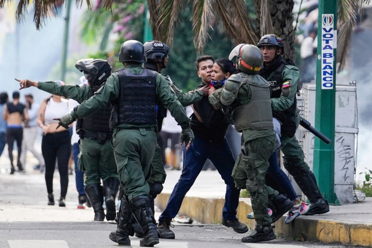 Police detain a protestor on the street outside