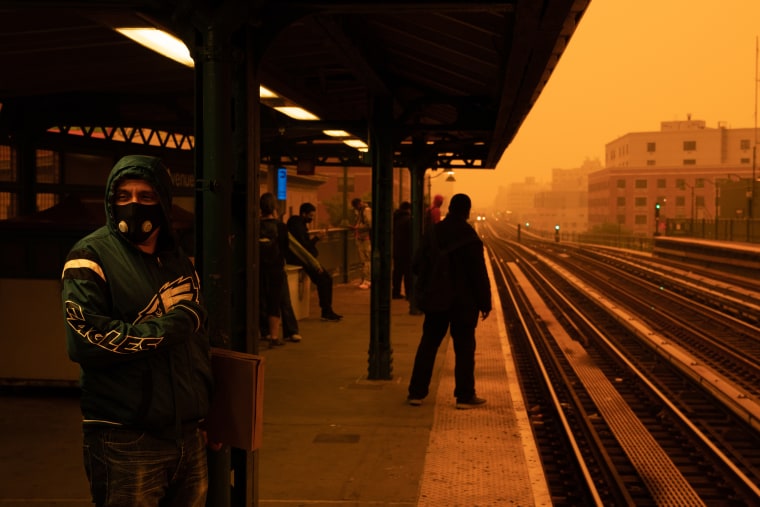 A person waiting for the subway wears a filtered mask as smoky haze from wildfires in Canada blankets a neighborhood. 