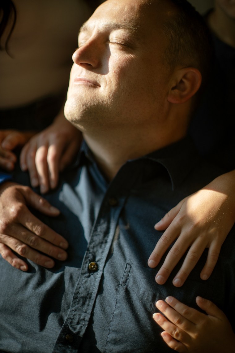 David Bennett Jr. closes his eyes while his family hugs him.