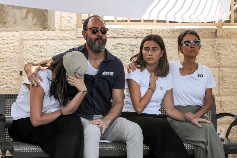 Jonathan Polin, Rachel Goldberg, and their two daughters sit side by side on a bench