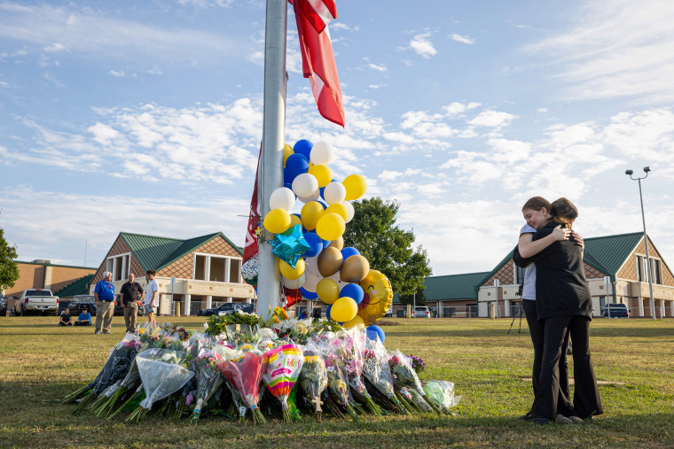 Students embrace near a makeshift memorial.