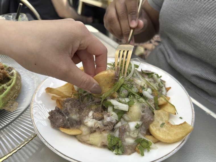 Diners dig into an order of pho poutine -- beef short rib, pho gravy and cheese curds over fries -- at Breaking Dawn restaurant in Los Gatos, Calif., on Sunday, Aug. 4, 2024.  