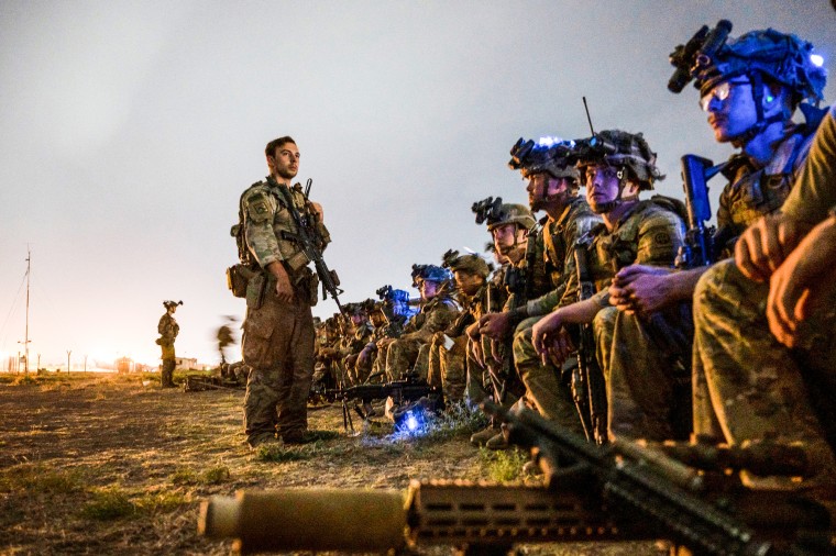 Soldiers sit and stand outside