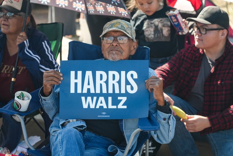 A man holds a Harris-Walz sign at a Navajo Nation parade in Window Rock, Ariz.