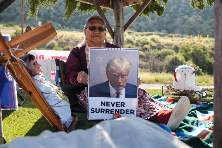 A woman holds a sign with a trophy shot of former President Donald Trump as she rides an Arizona GOP float in the Navajo Nation parade Saturday. 