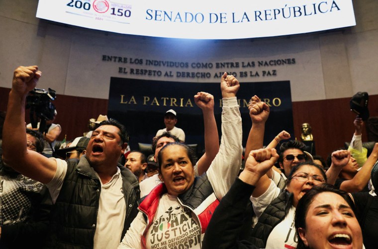 Demonstrators raise their fists after entering the Senate building as a highly contested judicial reform proposal is debated, following its approval by the Chamber of Deputies and backing by senators at the commission stage, in Mexico City