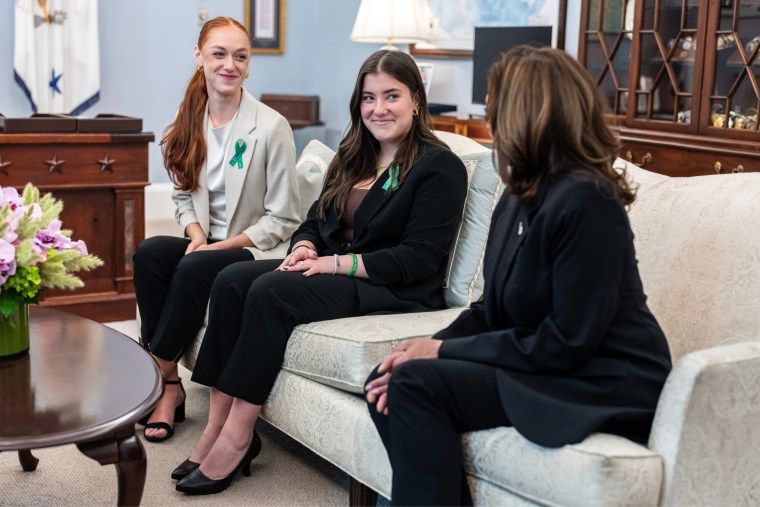 From left, Ella Sieber and Emma Ehrens sit next to Kamala Harris on a couch.