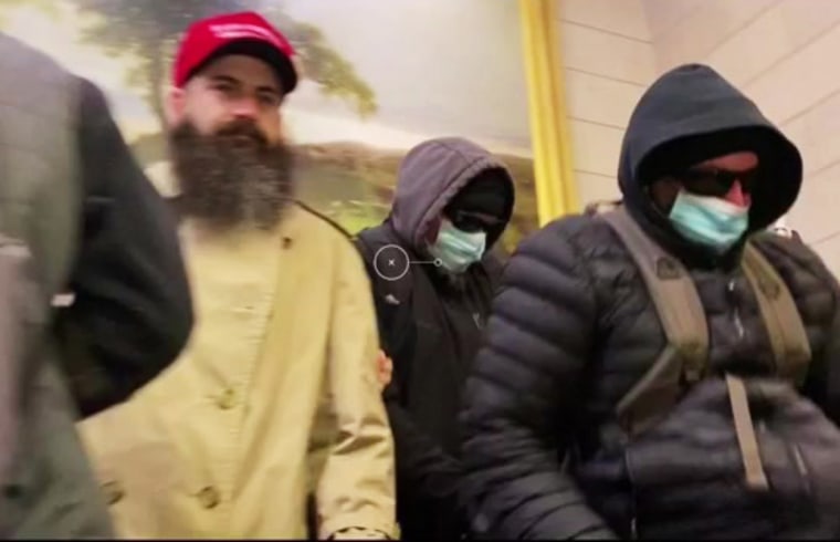 Dois homens que o FBI identificou como irmãos Walker, vistos à direita com máscaras, após agredir um fotógrafo do New York Times.