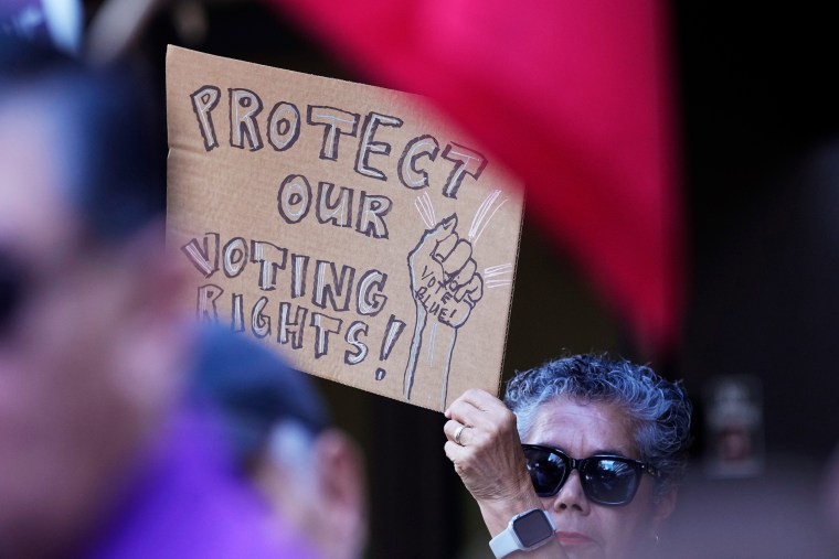 One supporter waves a sign that reads: "Protect Our Voting Rights" at a press conference 