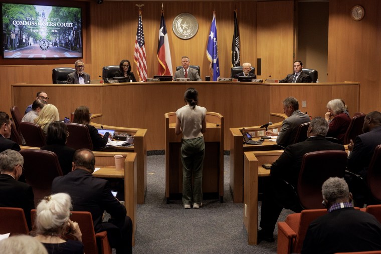 Woman stands at a podium at the Tarrant County commissioners meeting.