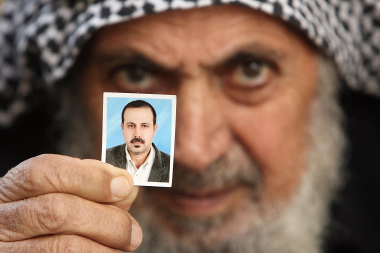 Father of senior Hamas military commander Mahmoud al-Mabhouh poses with his son's picture at his family house in the northern Gaza Strip