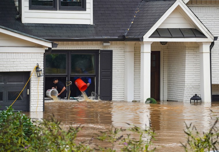 People toss buckets of water out of a flooded home on Sept. 27, 2024 in Atlanta.